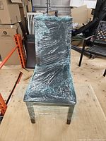 Front view of chair wrapped in protective film showing overall design