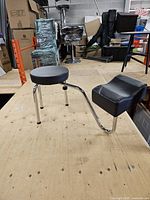 Full view of stool showing round seat, three chrome legs, curved support and leg rest