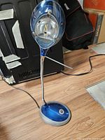 Full view of blue and silver desk lamp showing head, gooseneck, base