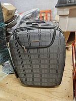 Front view of gray and black plaid Caggioni suitcase showing full pattern and zip pocket