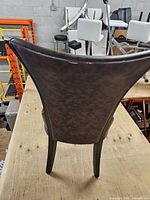 Rear view showing faux leather backrest and wood legs