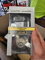 Front of retail box showing Defiant satin nickel deadbolt