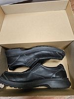 Pair of black leather slip-on shoes inside box