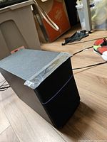 Front view of powered subwoofer showing black fabric grille and blue accent