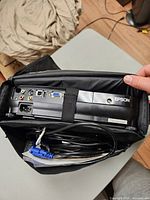 Projector rear panel inside carrying case showing input ports and cables