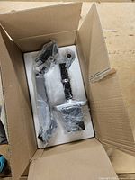 Box opened showing two wrapped monitor arms in foam