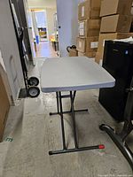 Full side view of folding table showing gray top and black folding legs