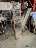 Mirror front wrapped in plastic leaning against shelving