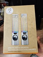 front of retail box displaying image of two silver dancing water speakers
