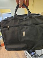 Front view showing GF logo plaque, exterior zip pocket, leather texture, handles