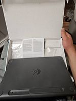 Back side of keyboard inside open box with paperwork visible