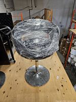 Full view of bar stool on pedestal base wrapped in plastic