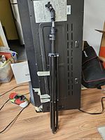 Collapsed Neewer light stand leaning upright