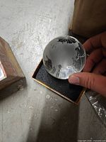 Crystal globe paperweight held above foam insert