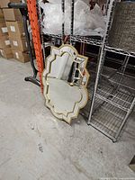 Front view of large quatrefoil mirror leaning against shelving