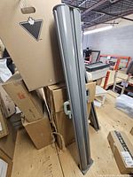 Front view of both aluminum pulldown screen housings standing upright among boxes