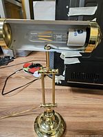 Full view of brass piano lamp with bulb installed