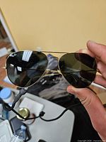 Front view of gold Ray-Ban Aviator sunglasses showing green lenses and attached neck strap