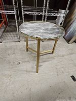 Full view of table showing round glass top and gold metal base