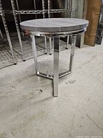Full view of round side table showing top, legs, and overall condition