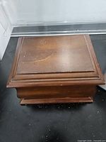 Closed wooden jewelry box showing cherry finish and surface scratches
