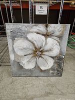 Front view of square canvas showing white floral design with textured paint and metallic accents