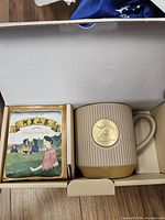Open gift box showing mug and sealed tea packet