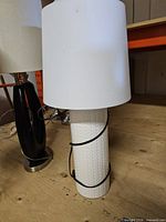 Front view of white ceramic table lamp with drum shade and power cord