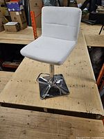 Front view of white faux leather bar stool on chrome pedestal and base