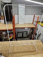 Front view of white metal garment rack on workbench