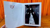 Open display box showing Barbie doll in black coat and white underskirt