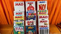 Front view of twelve bagged MAD magazines on rack displaying various covers