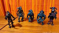 Five upright xenomorph figures on tabletop