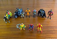 Group shot of all action figures and Batcycle on wooden surface