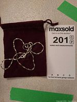 Necklace coiled on velvet pouch beside lot card