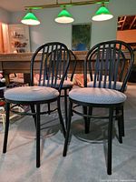 Two of the four black metal dining chairs with gray upholstered seats shown together