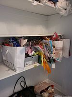 Shelf with numerous paper gift bags, tissue, ribbons and accessories in shopping bags