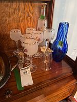 Lot overview showing six frosted wine glasses, clear decanter, cobalt blue vase, clear bell