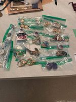 Grouped sealed bags showing quantity and variety of earrings and brooches