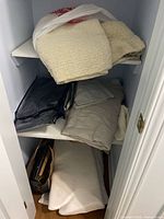 Closet shelves with folded throw, sheet set in zippered bag, loose linens and memory-foam pillow