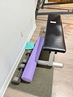 bench, dumbbells, foam roller, towel on mat