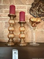 Full lot showing both candlesticks with candles and martini glass with gold fruit