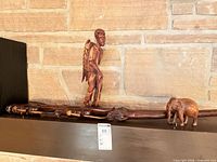 Wide shot showing walking stick, human figurine and elephant on shelf