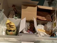 Drawer with three boxed figurines: children in raincoats, child violinist, bubble-wrapped bunny