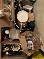 Assorted kitchen items in bins and boxes including pans, jars, plastic containers