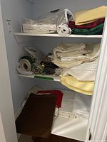 Closet shelves with stacked and rolled assorted linens in multiple colours