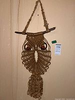 Full view of macramé owl wall hanging showing jute construction, driftwood perch, hanging loop