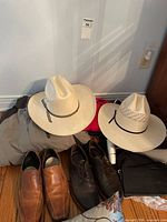Overview: two straw hats, Columbia jacket beneath, two pairs leather shoes, red garment