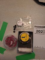 Group shot showing all components: red beads container, purse hook in box, brooch, black beads, packaging