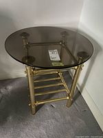first table showing smoked glass top, brass frame, lower stretchers